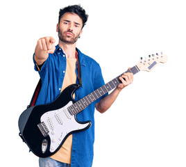 Obraz premium Young hispanic man playing electric guitar pointing with finger to the camera and to you, confident gesture looking serious