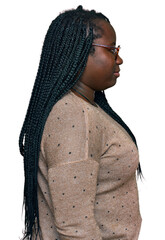 Fototapeta premium Young black woman with braids wearing casual clothes and glasses looking to side, relax profile pose with natural face with confident smile.