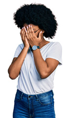 Young african american woman wearing casual white t shirt with sad expression covering face with hands while crying. depression concept.