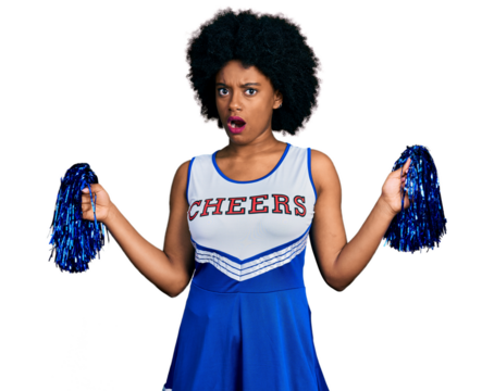 Young african american woman wearing cheerleader uniform using pompom in shock face, looking skeptical and sarcastic, surprised with open mouth
