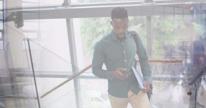 Animation of african american businessman using smartphone over cityscape