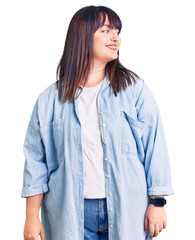 Young plus size woman wearing casual clothes looking away to side with smile on face, natural expression. laughing confident.