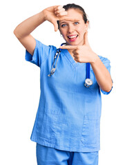 Young beautiful blonde woman wearing doctor uniform and stethoscope smiling making frame with hands and fingers with happy face. creativity and photography concept.