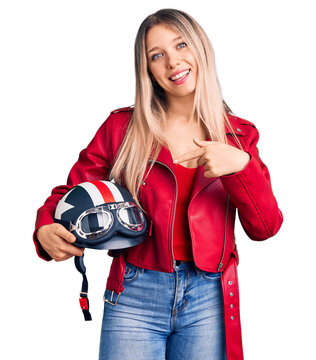 Young beautiful blonde woman holding motorcycle helmet smiling happy pointing with hand and finger