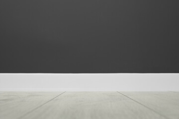 White plinth on laminated floor near black wall indoors