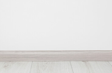 Wooden plinth on laminated floor near white wall indoors