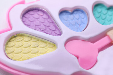 Decorative cosmetics for kids. Eye shadow palette with applicator as background, closeup
