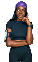 Young african american woman wearing sportswear serious face thinking about question with hand on chin, thoughtful about confusing idea