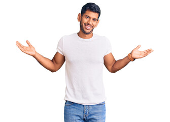 Young latin man wearing casual clothes clueless and confused expression with arms and hands raised. doubt concept.
