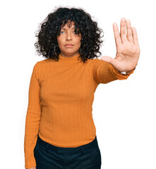 Young hispanic woman wearing casual clothes doing stop sing with palm of the hand. warning expression with negative and serious gesture on the face.