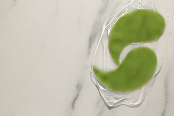 Green under eye patches with gel on white marble background, top view and space for text. Cosmetic product