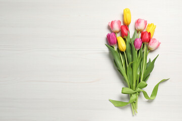 Beautiful tulips on white wooden table, flat lay. Space for text
