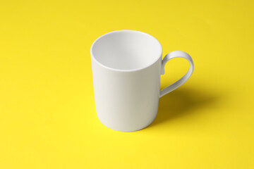 One white ceramic mug on yellow background