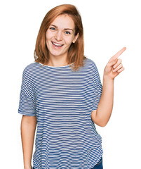 Young caucasian woman wearing casual clothes with a big smile on face, pointing with hand and finger to the side looking at the camera.