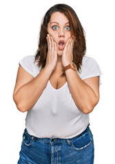 Young plus size woman wearing casual white t shirt afraid and shocked, surprise and amazed expression with hands on face