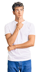 Young handsome man wearing casual white tshirt thinking concentrated about doubt with finger on chin and looking up wondering