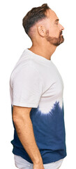Fototapeta premium Handsome middle age man wearing casual tie dye tshirt looking to side, relax profile pose with natural face with confident smile.