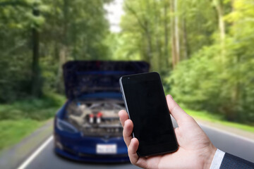Man use mobile phone, blur image of the car is broken down as background.