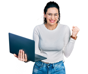 Young hispanic woman working using computer laptop screaming proud, celebrating victory and success very excited with raised arm