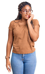 Young african american woman with braids wearing casual clothes and glasses looking stressed and...