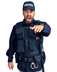 Young hispanic man wearing police uniform pointing displeased and frustrated to the camera, angry and furious with you