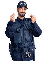 Young hispanic man wearing police uniform doing money gesture with hands, asking for salary payment, millionaire business