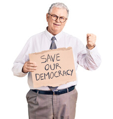 Senior grey-haired man wearing business clothes holding save our democracy protest banner screaming proud, celebrating victory and success very excited with raised arms