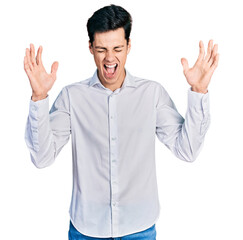 Naklejka premium Young hispanic business man wearing business clothes celebrating mad and crazy for success with arms raised and closed eyes screaming excited. winner concept
