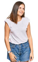 Obraz premium Young caucasian woman wearing casual white tshirt looking away to side with smile on face, natural expression. laughing confident.