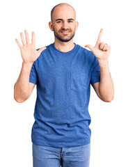 Young handsome man wearing casual t shirt showing and pointing up with fingers number seven while smiling confident and happy.