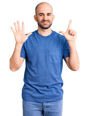 Naklejka premium Young handsome man wearing casual t shirt showing and pointing up with fingers number seven while smiling confident and happy.