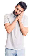 Young handsome man with beard wearing casual polo sleeping tired dreaming and posing with hands together while smiling with closed eyes.