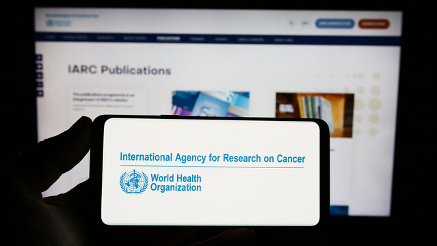 Stuttgart, Germany - 07-04-2023: Person holding smartphone with logo of International Agency for Research on Cancer (IARC) on screen in front of website. Focus on phone display.