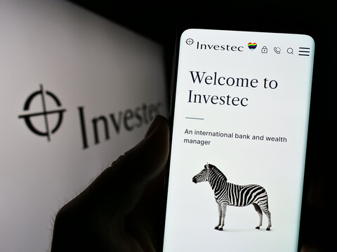 Stuttgart, Germany - 07-04-2023: Person holding cellphone with logo of financial services company Investec Group on screen in front of business webpage. Focus on phone display.