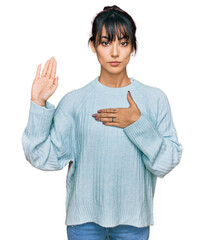 Young hispanic woman wearing casual clothes swearing with hand on chest and open palm, making a...