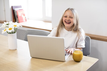 
Smiling little girl having video call in remote class with teacher using laptop, happy little kid greeting with tutor, learning online on computer, home learning concept