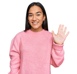 Young asian woman wearing casual winter sweater showing and pointing up with fingers number five...