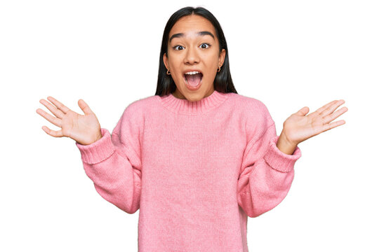 Young asian woman wearing casual winter sweater celebrating crazy and amazed for success with arms raised and open eyes screaming excited. winner concept