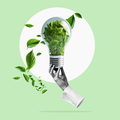 Hand holds a green energy lightbulb filled with leaves. Renewable green energy concept.