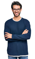 Fototapeta premium Young hispanic man wearing casual clothes and glasses happy face smiling with crossed arms looking at the camera. positive person.