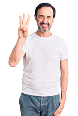 Fototapeta premium Middle age handsome man wearing casual t-shirt showing and pointing up with fingers number three while smiling confident and happy.