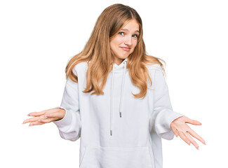 Beautiful young caucasian girl wearing casual sweatshirt clueless and confused expression with arms...