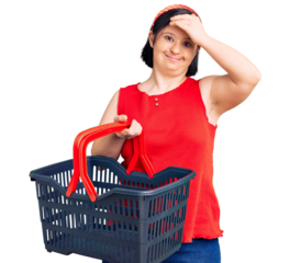 Brunette woman with down syndrome holding supermarket shopping basket stressed and frustrated with hand on head, surprised and angry face