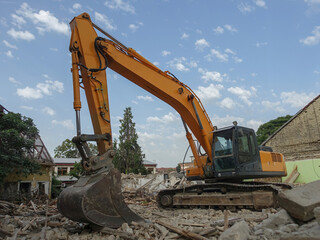 Heavy yellow excavator machine bagger  clears the ground where the house was demolished