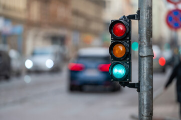 view of city traffic with traffic lights, in the foreground a semaphore with a green light, closeup
