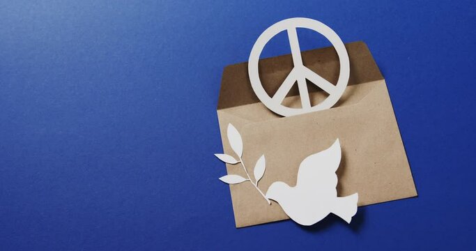 Close up of white dove with leaf, white peace sign, envelope and copy space on blue background