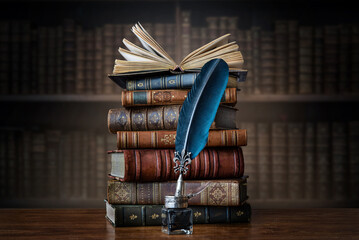 Old books ,quill pen and vintage inkwell on wooden desk in old library. Ancient books historical...