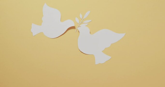 Close up of white doves with leaf and copy space on yellow background