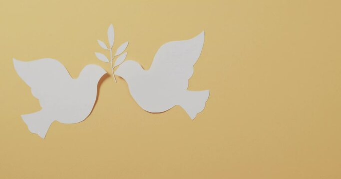 Close up of white doves with leaf and copy space on yellow background