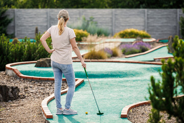 Woman playing mini golf at course. Summer sport and leisure activity